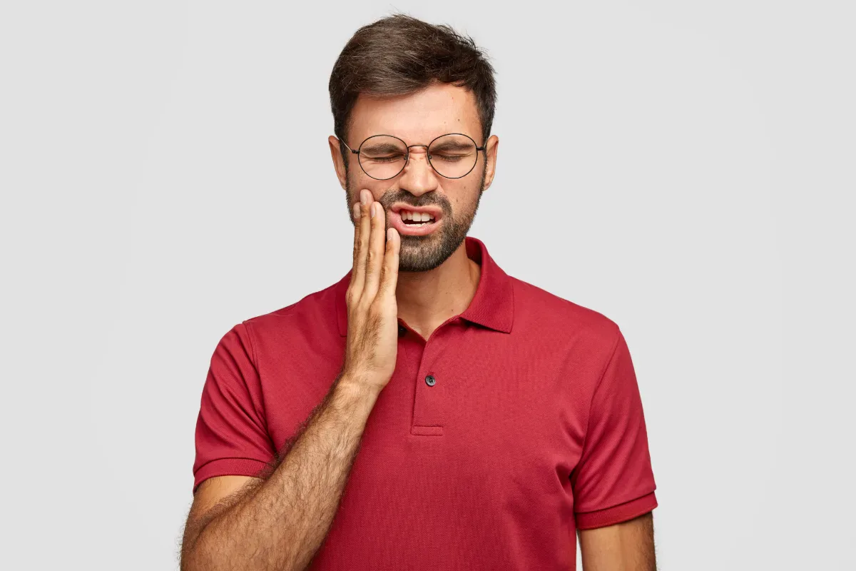 Woman in pain holding her jaw, in need of emergency dental care in Woodbridge